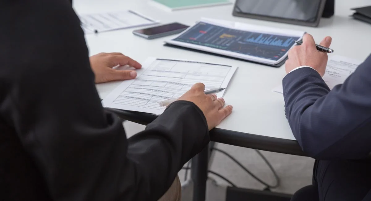 Close-up of professionals reviewing documents in an office setting, focused on analytics.