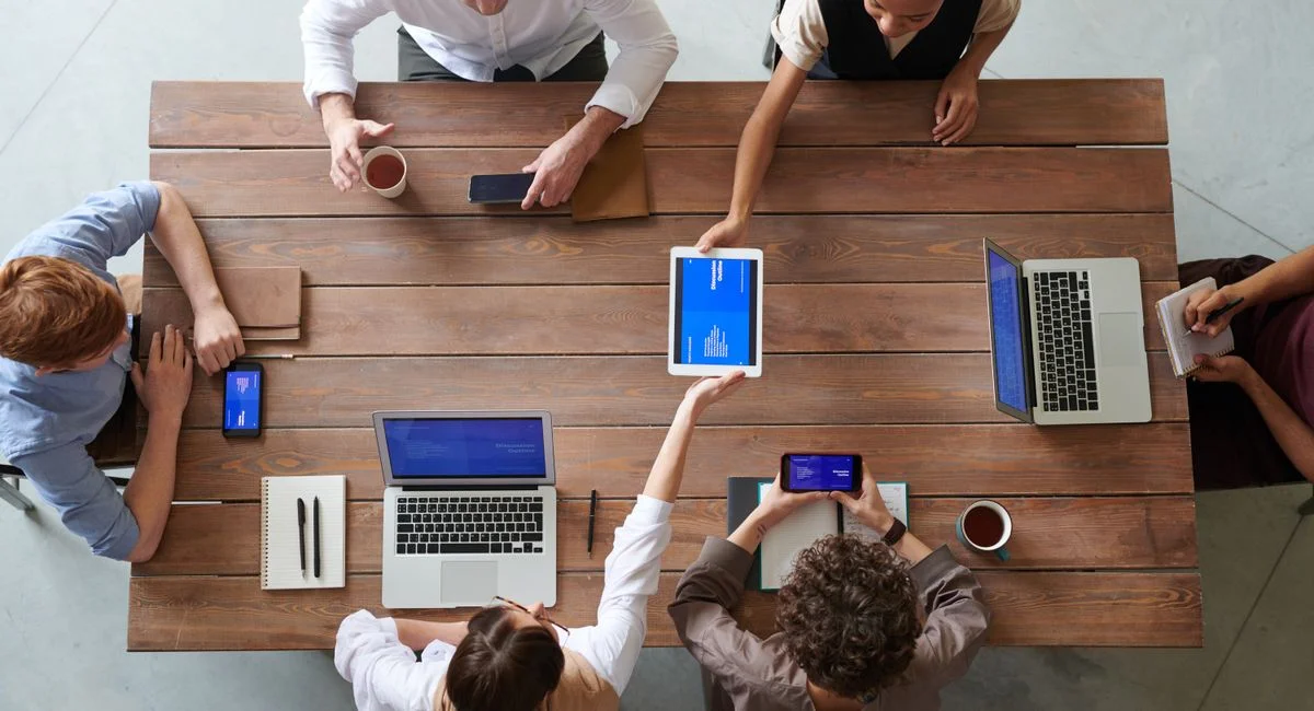 A diverse group of professionals engaged in a productive office meeting using digital devices.