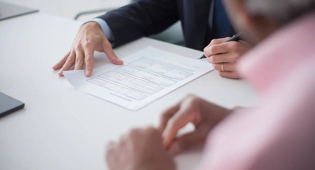 Two professionals engaging in a business meeting, signing documents for a consulting agreement.