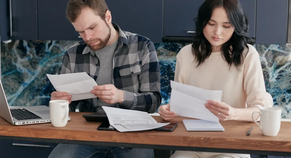 A couple reviewing financial documents at home, showcasing concern and focused collaboration.