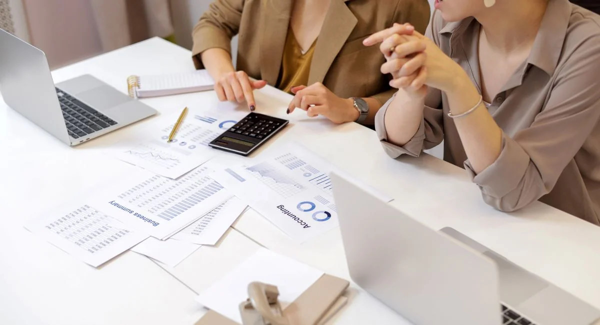 Two professionals collaborating on financial documents in a modern office setting.