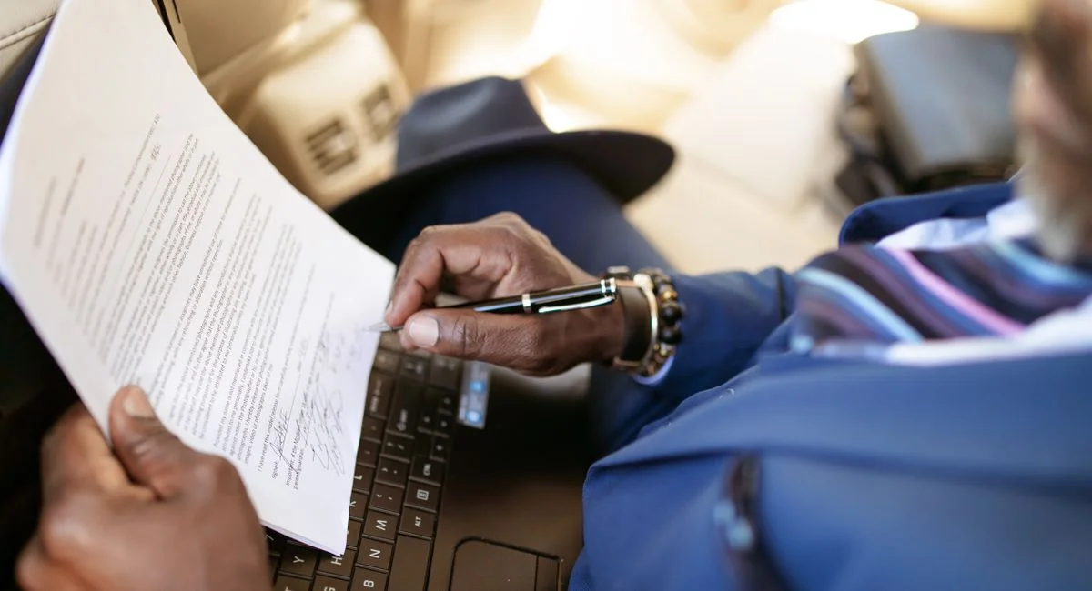 Close-up of a professional in blue attire reviewing a document on a laptop, highlighting modern work setups.