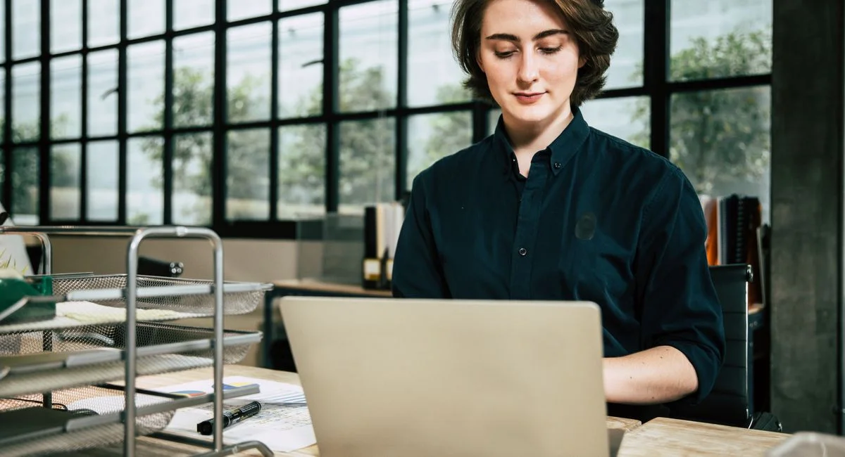 Professional woman using laptop in a stylish office environment, focused on work.