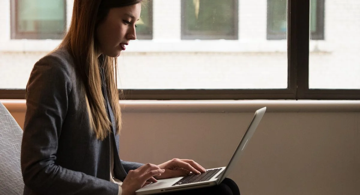 Professional woman using laptop in modern indoor setting. Ideal for business or technology themes.