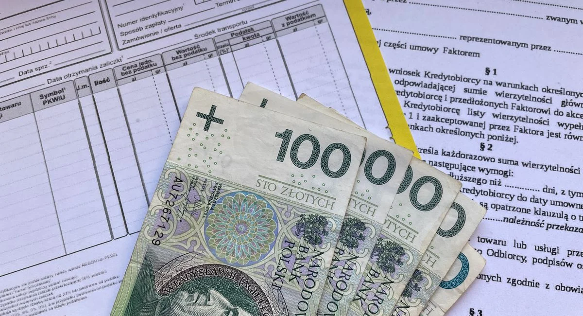 Polish 100 Zloty banknotes on VAT invoice and factoring agreement forms.