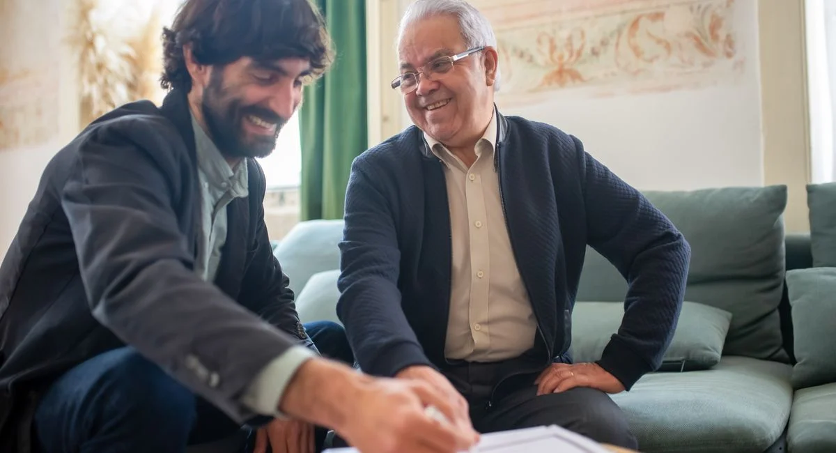 An advisor and elderly client discussing documents during a consulting session indoors.