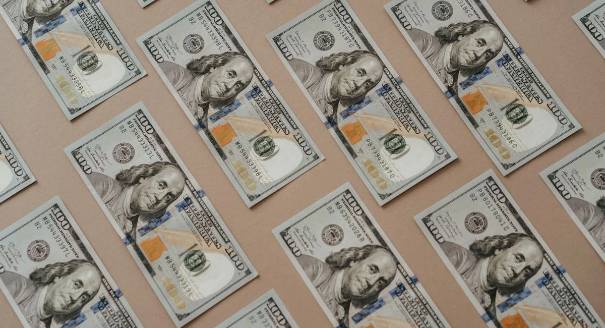 Close-up of multiple US dollar bills arranged in a grid pattern.