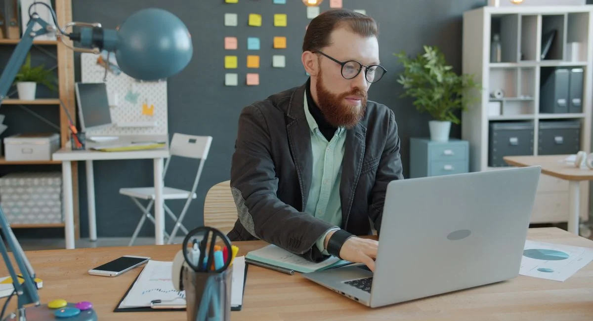 Businessman analyzing data on laptop in modern office setting.