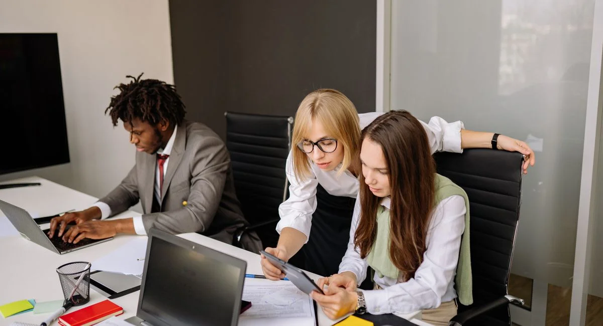 Business team collaborating in a modern office setting with laptops and tablets.