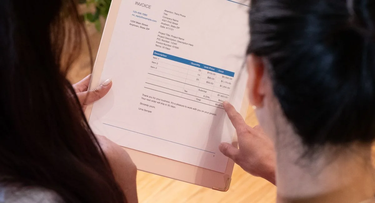 Two individuals reviewing an invoice together in a modern office setting.