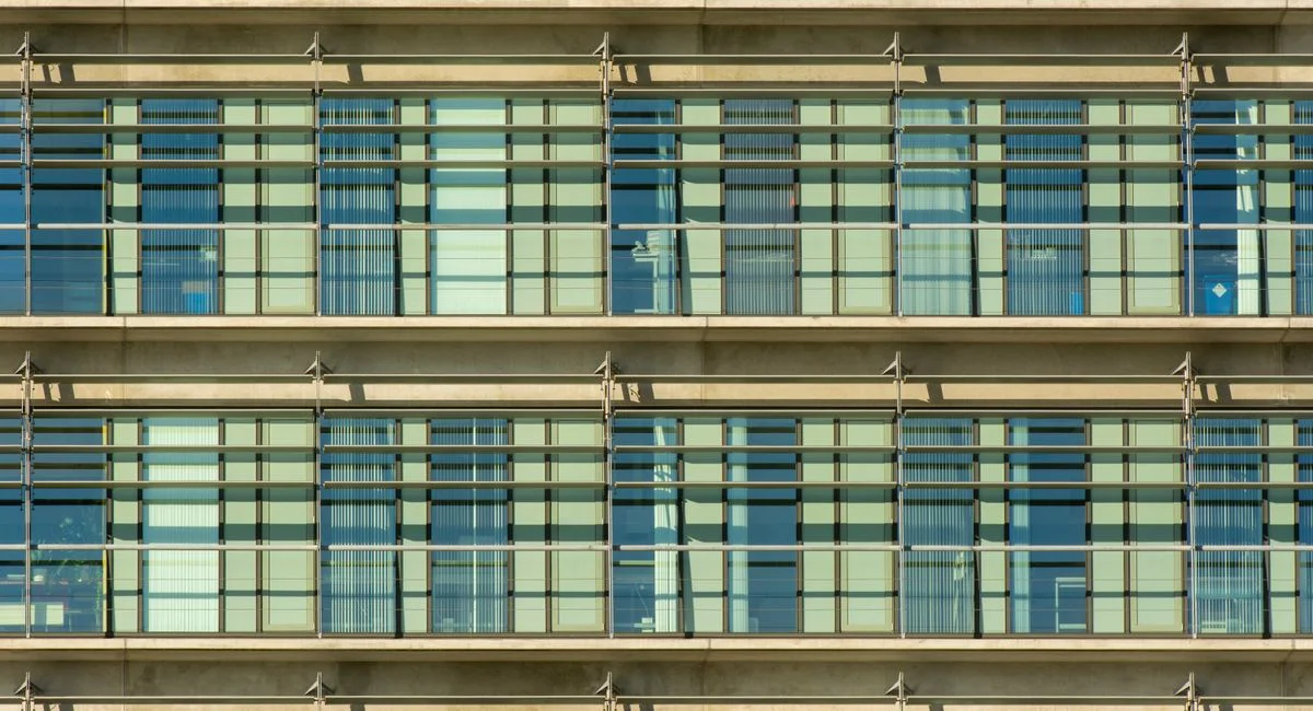 Close-up of a modern building facade with repetitive grid pattern and glass windows.